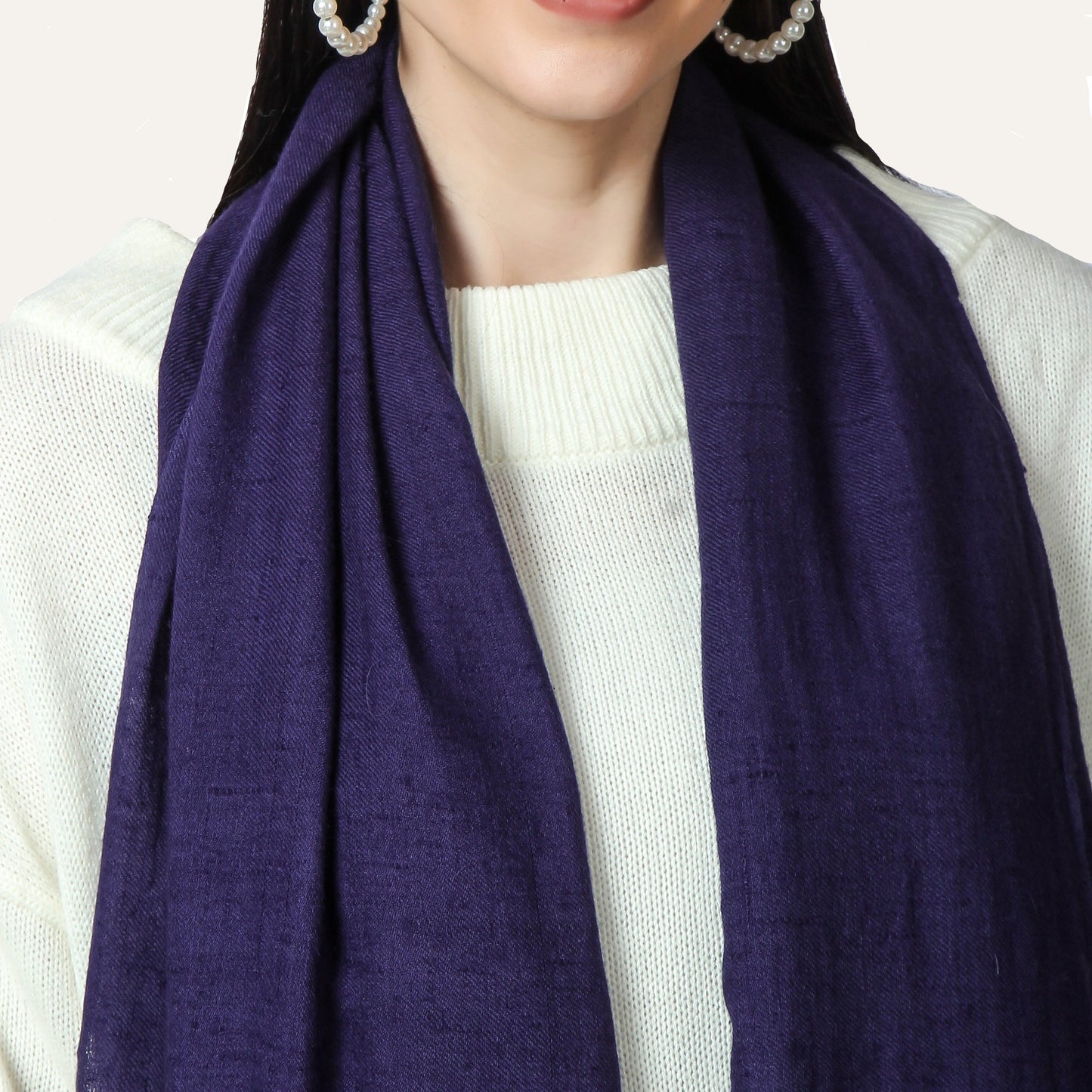 Person wearing a purple scarf and white sweater on a white background