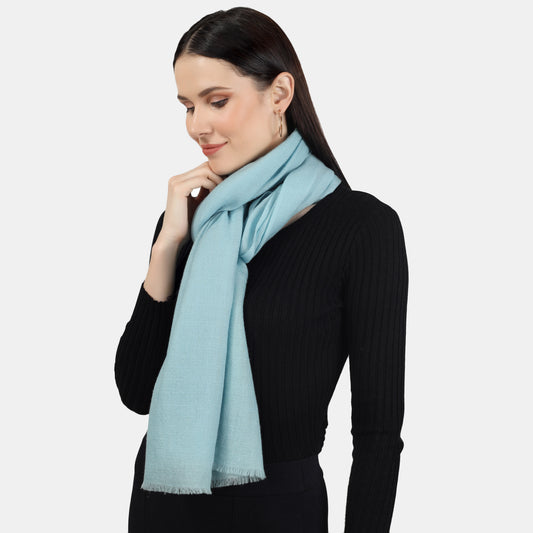 A woman wearing a Turquoise cashmere scarf in tugging it around the neck