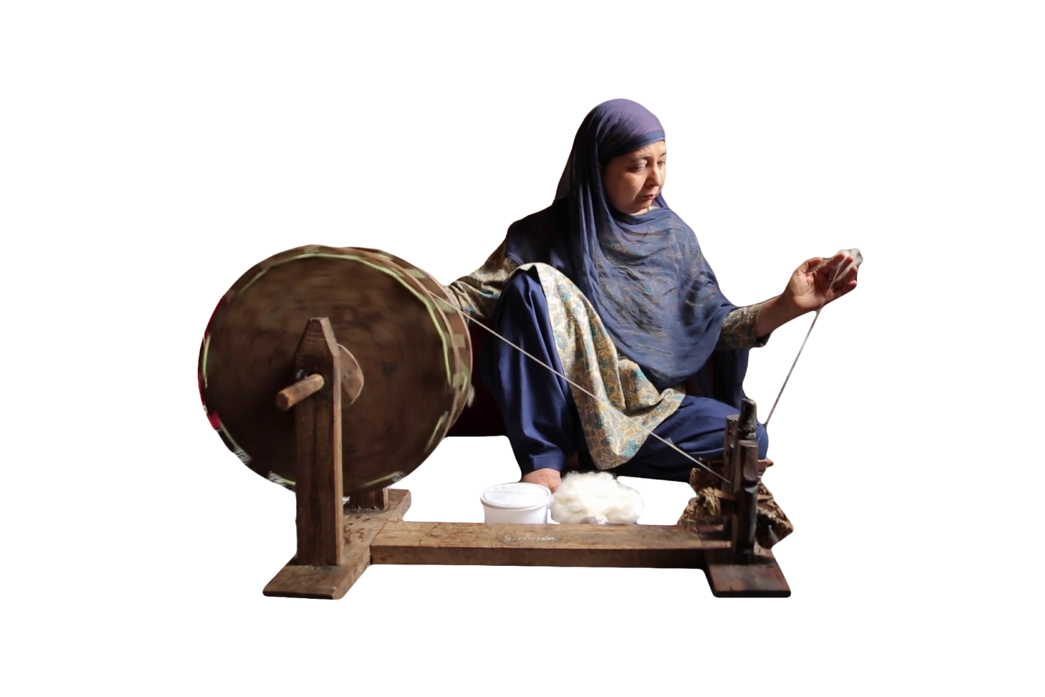 Woman behind a spinning wheel in the remote location of Kashmir who is spinning the cashmere fibres into a yarn