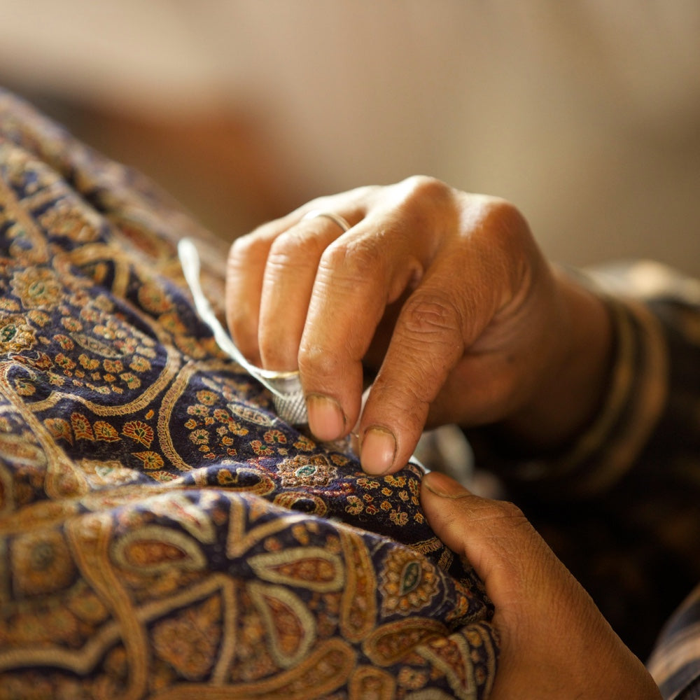 Pashmina Shawl Soon Needle work embroidery done by a Kashmiri Artisan in Remote village area of Kashmir, the image shows a navy blue pashmina shawl being embroidered by a needle by Kashmiri artisan.