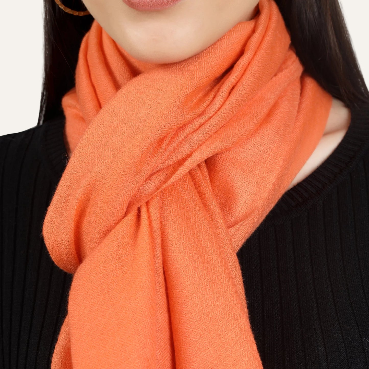 Brunt orange color scarf worn across neck by a woman