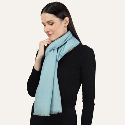 Turquoise cashmere scarf draped around the neck of a woman