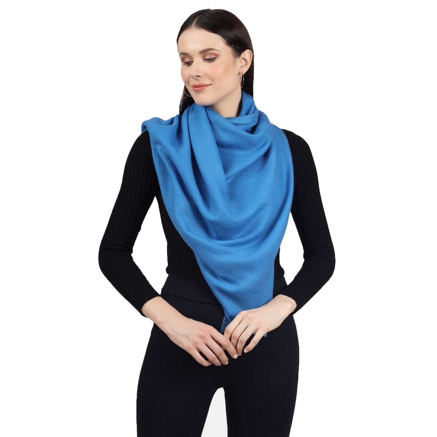 Image of a woman wearing a blue cashmere scarf wrapped around her neck in a stylish and elegant way. The scarf is folded in a neat and precise manner, and the blue color adds a pop of color to the woman's outfit. The scarf appears to be made with high-quality material, and its soft and luxurious texture is visible in the image. The woman's expression is confident and sophisticated, with a subtle smile on her lips.