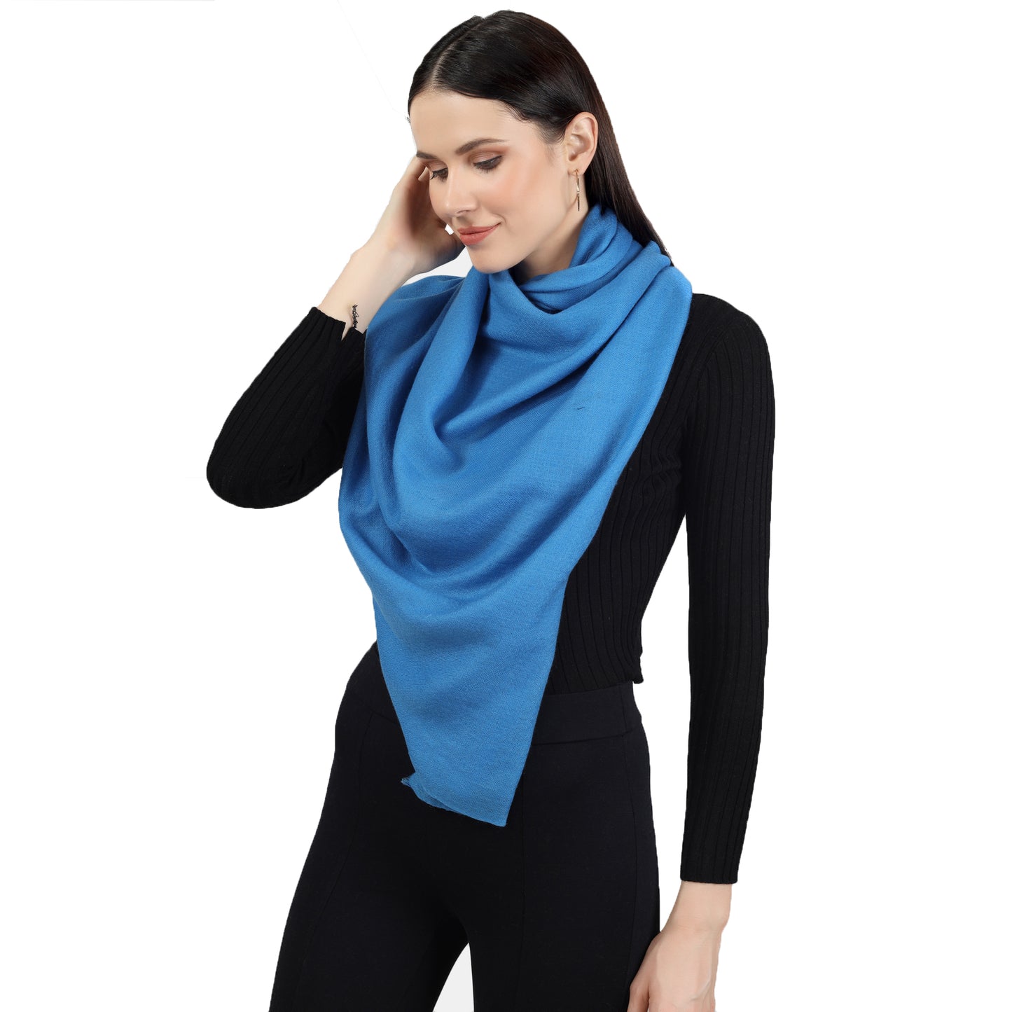 Image of a woman wearing a blue cashmere scarf wrapped around her neck in a stylish and elegant way. The scarf is neatly folded and draped around her neck, with one end slightly longer than the other, adding a touch of asymmetry to the look. The blue color adds a pop of color to the woman's outfit, and the soft and luxurious texture of the scarf is visible in the image. The woman's expression is confident and poised, with a subtle smile on her lips.