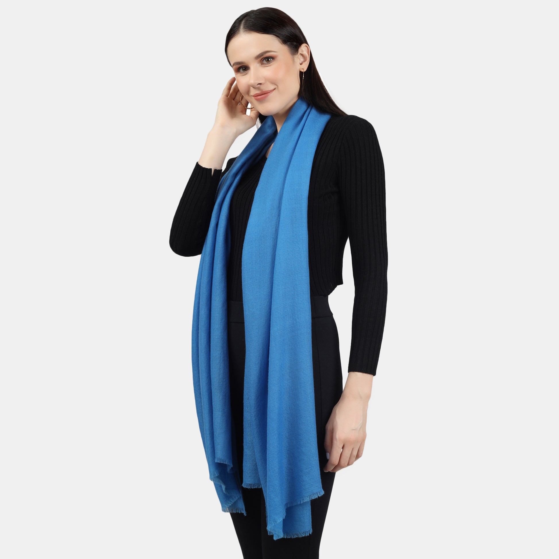 Image of a woman wearing a blue cashmere scarf draped around her neck, with both ends of the scarf hanging on the two sides of her shoulders. The scarf appears to be made with high-quality material and its soft and luxurious texture is visible in the image. The