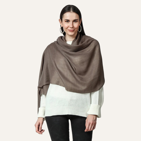 A woman wearing a merlin cashmere scarf with a white top and black pants.