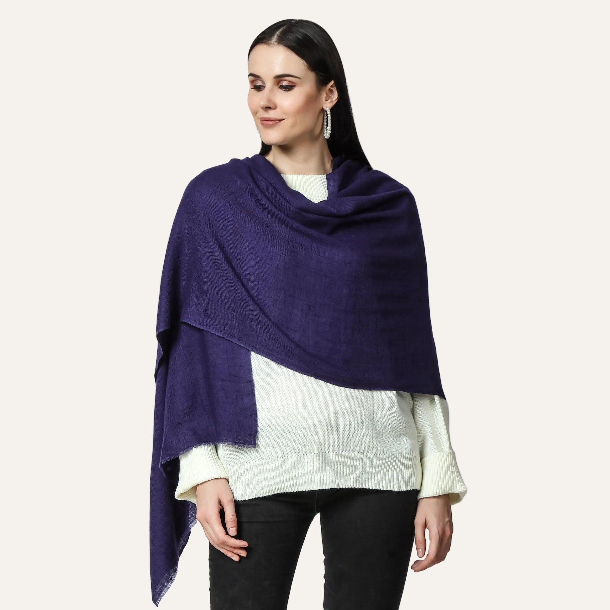 A woman wearing a navy cashmere scarf with a white top and black pants.