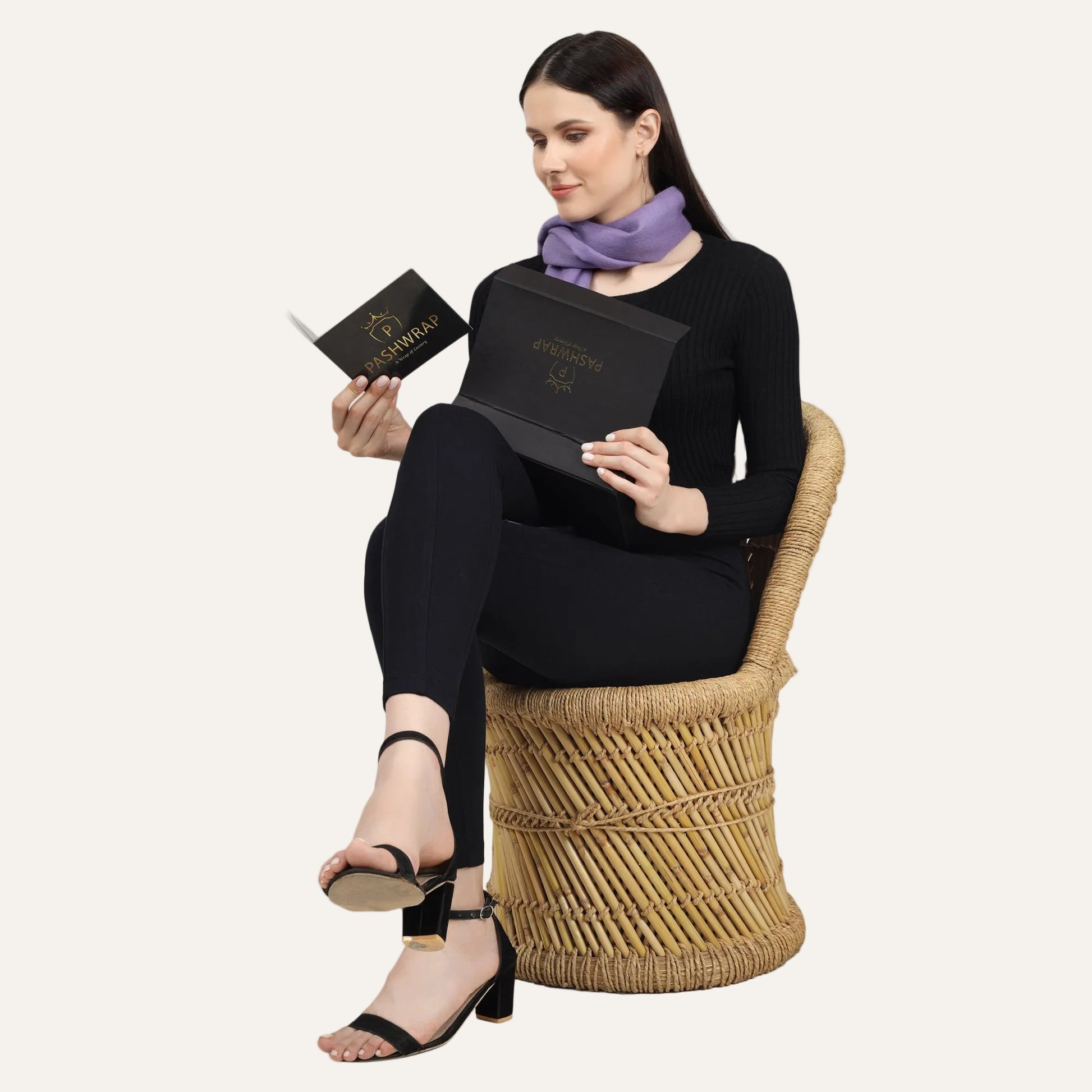 A woman reading the booklet of Pashwrap cashmere Scarf