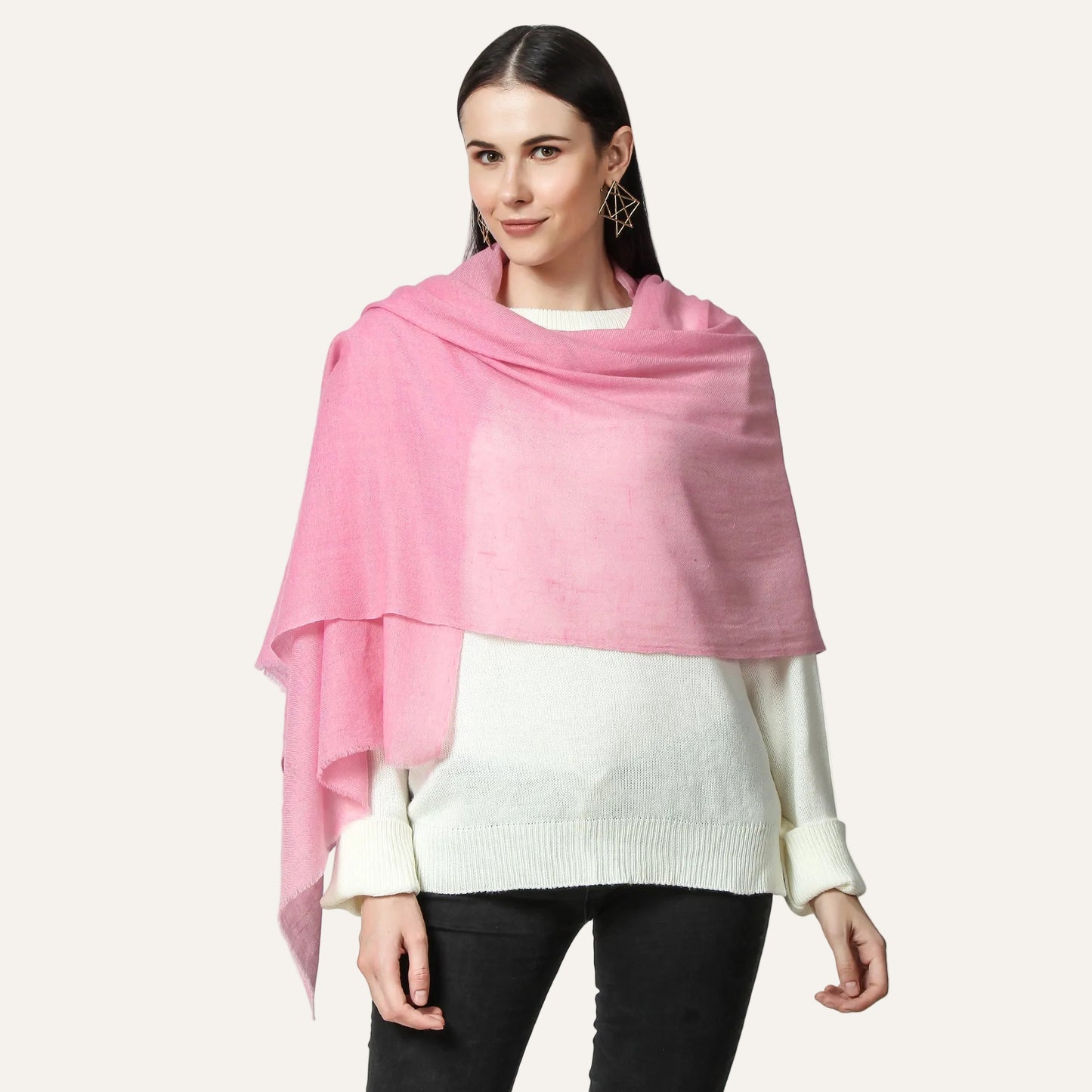 A woman wearing a pink cashmere scarf with a white sweater and black pants.