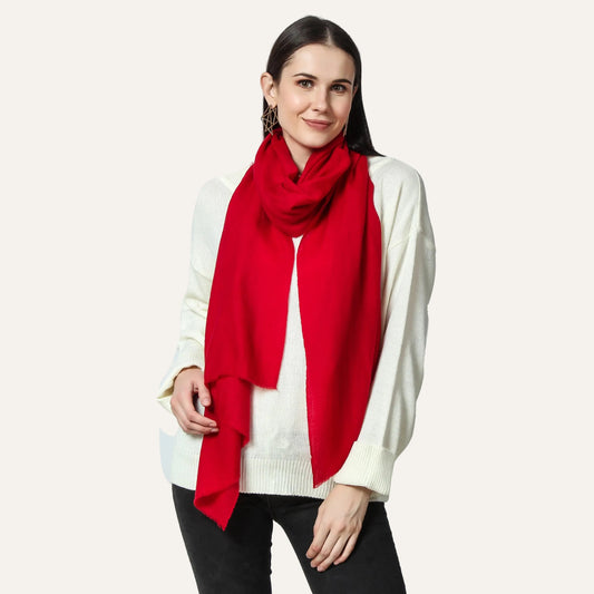 A woman wearing a red cashmere scarf with a white sweater and black pants, posing against a white background.