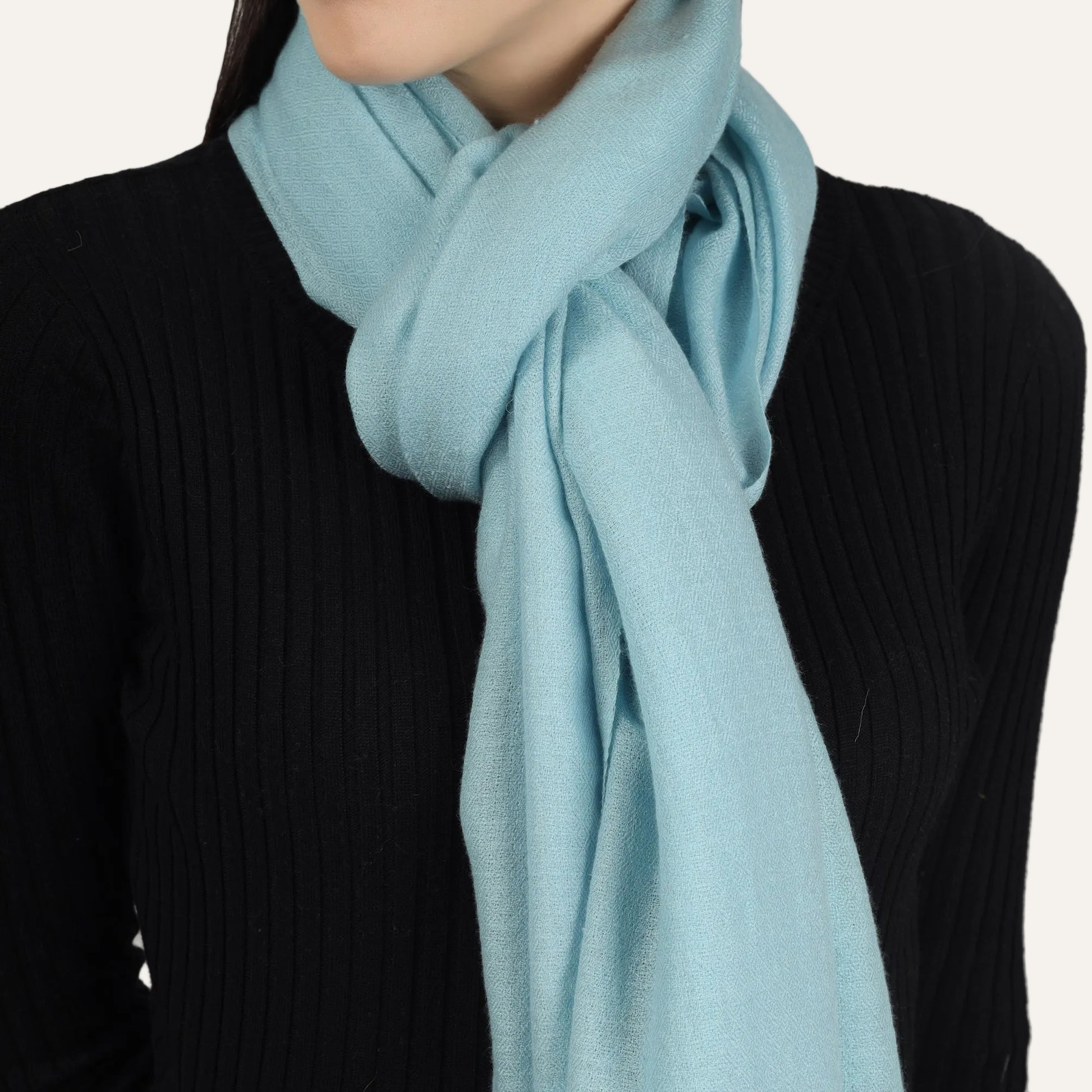 A cashmere Turquoise scarf worn by a woman over a black sweater