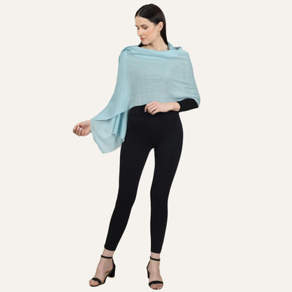 Woman wearing a turuoise cashmere scarf over a black dress