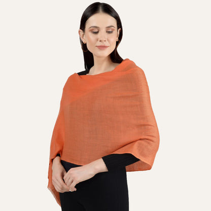 A woman wearing a handwoven orange cashmere scarf with a V-neck design.